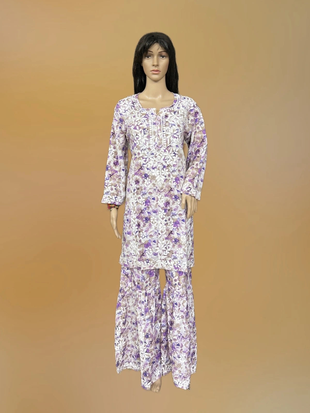 Lucknowi chikankari A mannequin wearing a long-sleeve white kurta and matching pants set with a purple floral pattern, set against a solid tan background.