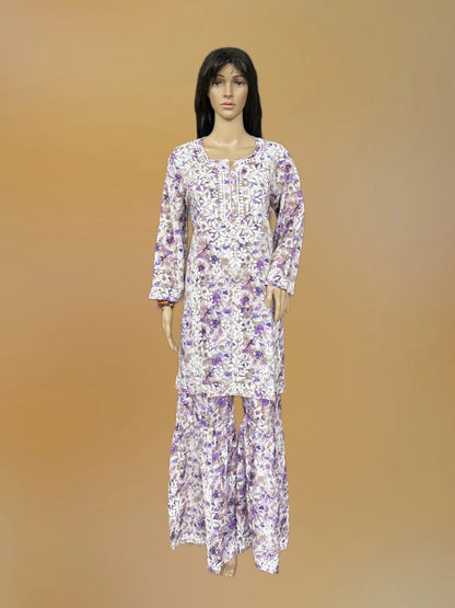 Lucknowi chikankari A mannequin wearing a long-sleeve white kurta and matching pants set with a purple floral pattern, set against a solid tan background.