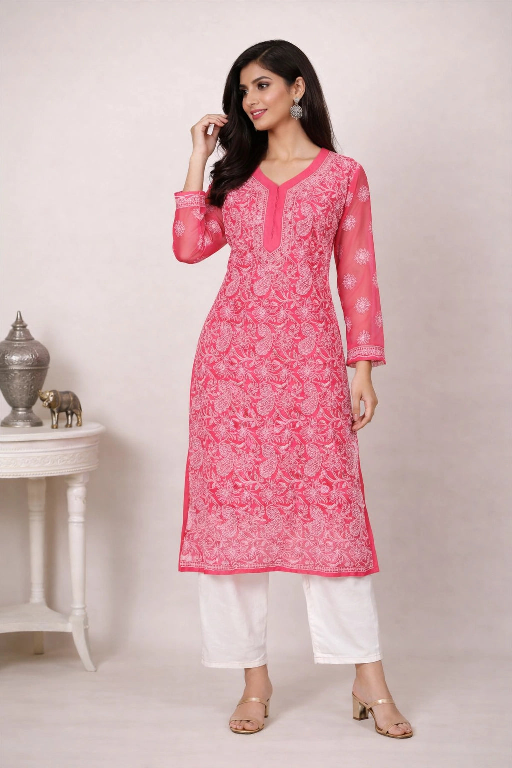 Woman wearing a pink kurta with white pants against a plain background