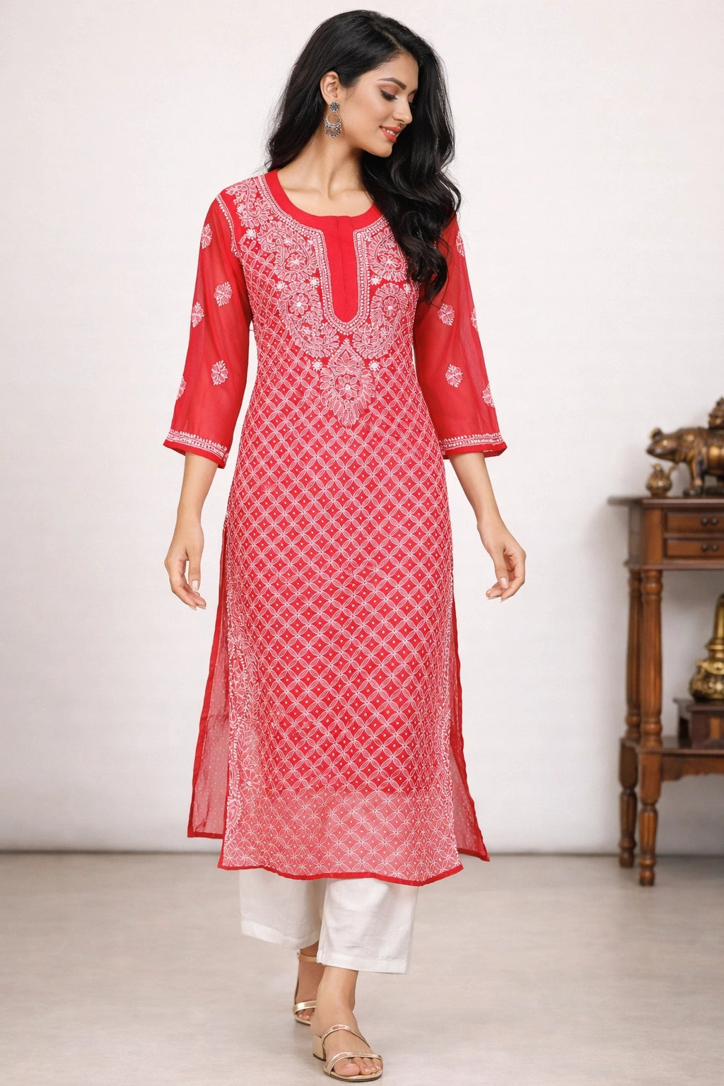 Woman wearing a red and white embroidered kurta with white pants against a plain background