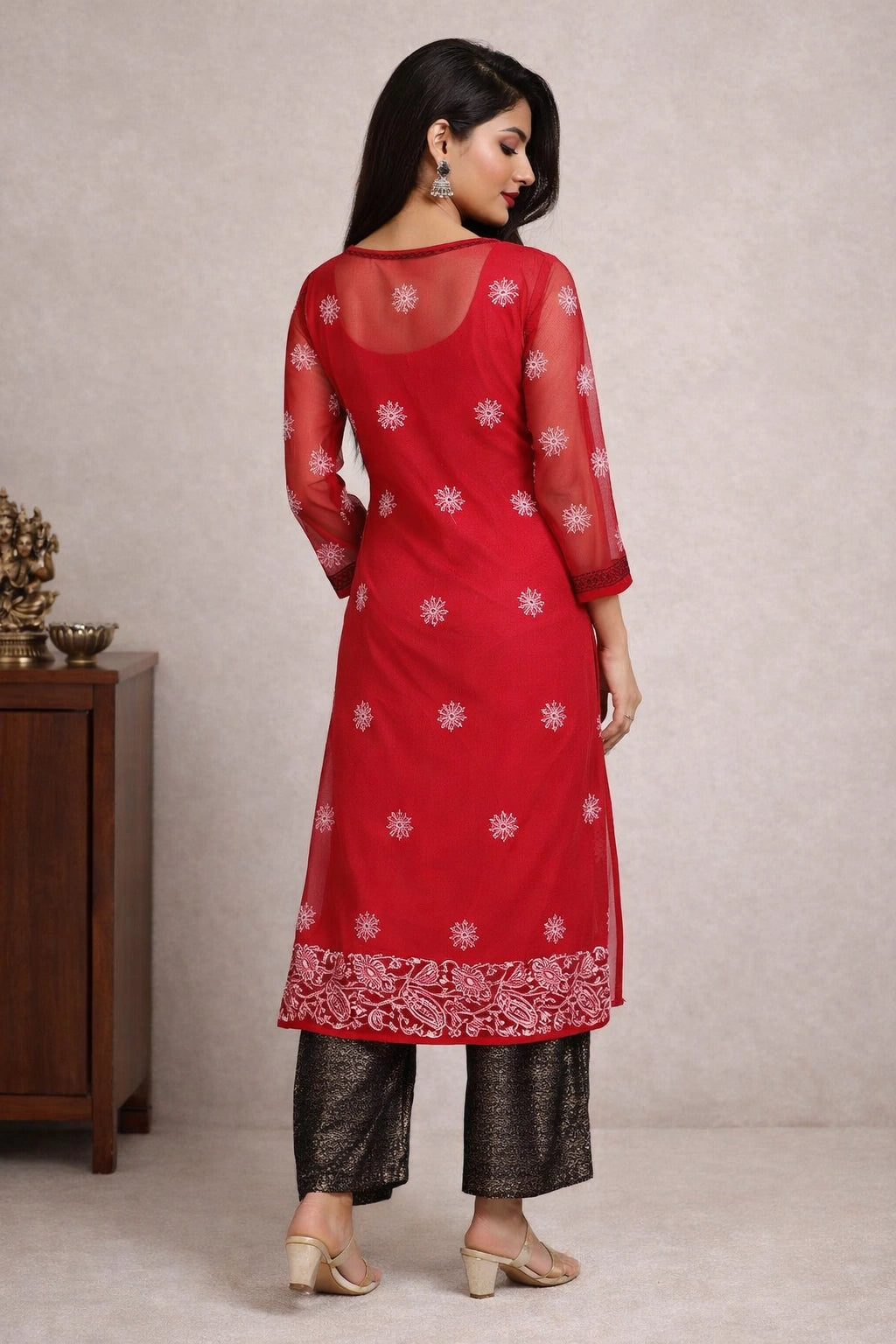 Woman wearing a pink embroidered kurta with white pants in a neutral setting