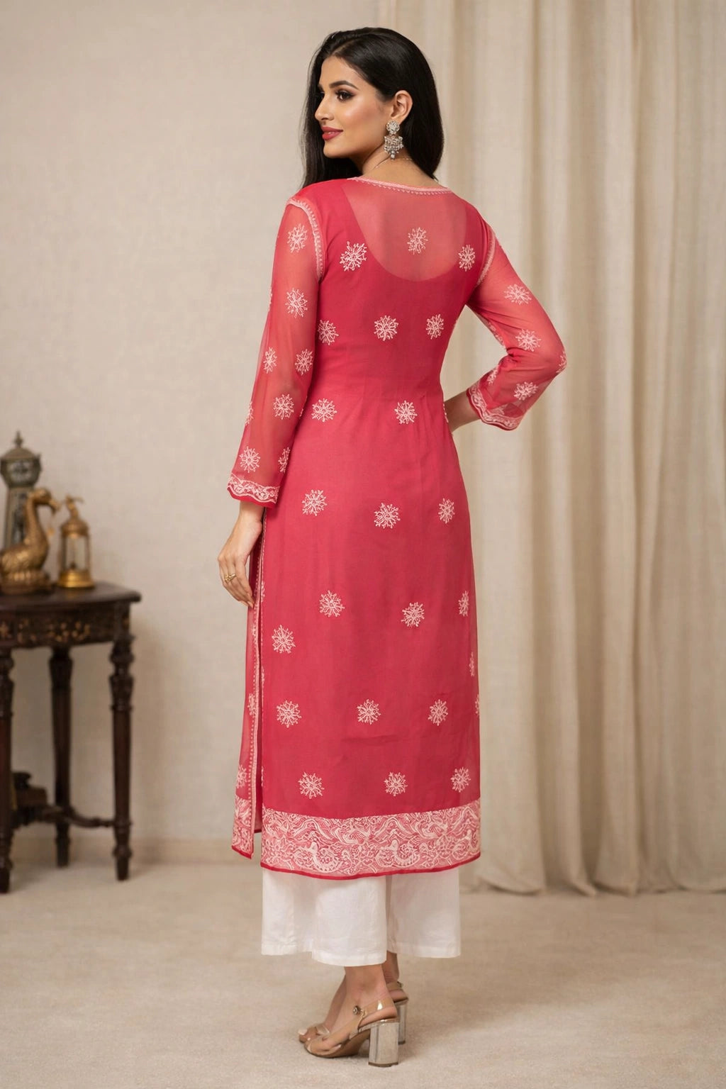 Woman wearing a pink embroidered kurta with white pants in a neutral setting
