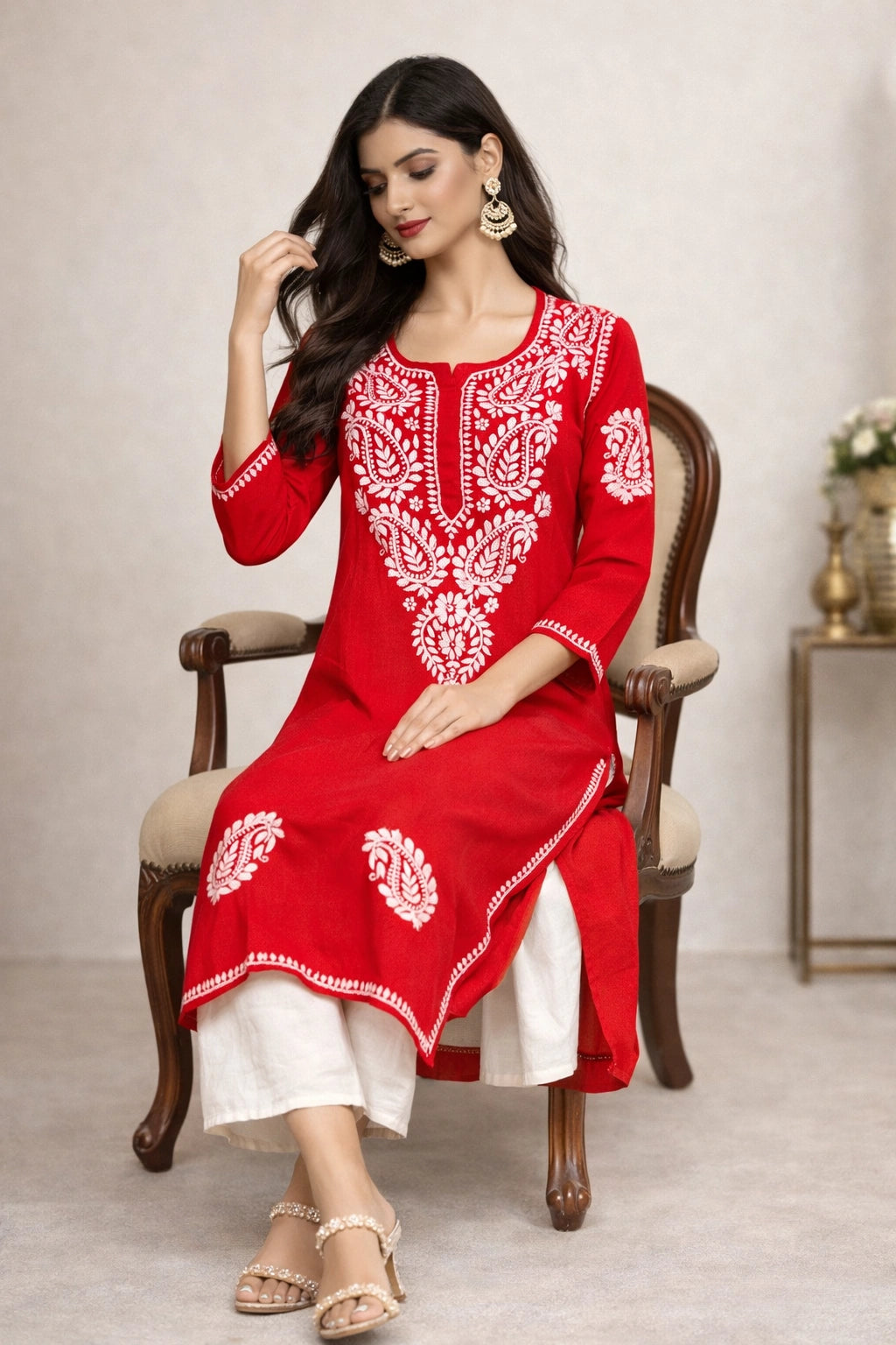Woman wearing a red and white embroidered kurta sitting on a chair.