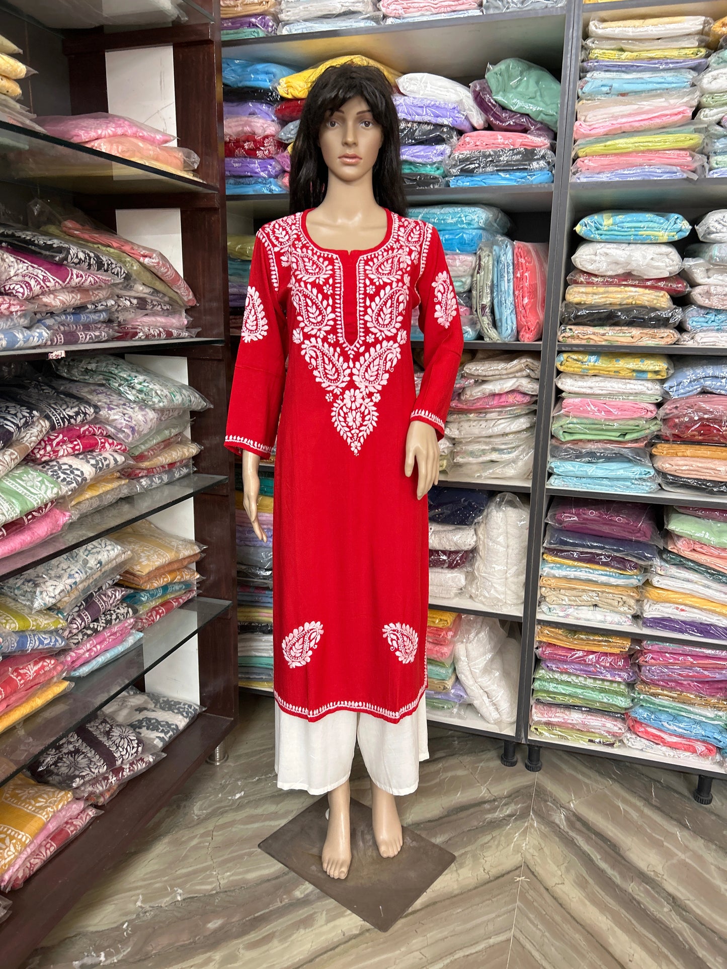 Mannequin wearing a red embroidered dress in a fabric store