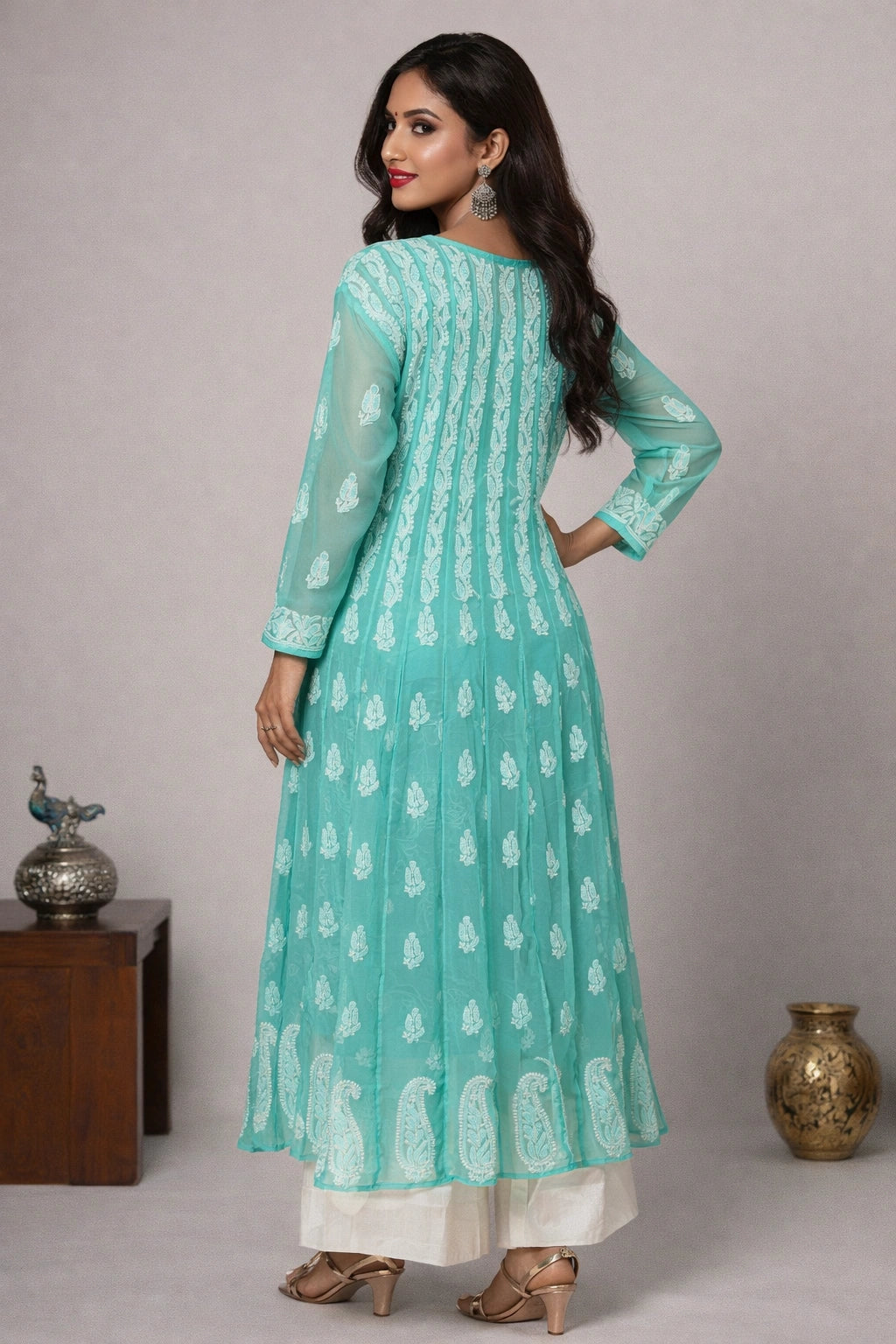 Woman wearing a light blue traditional outfit with white patterns against a neutral background