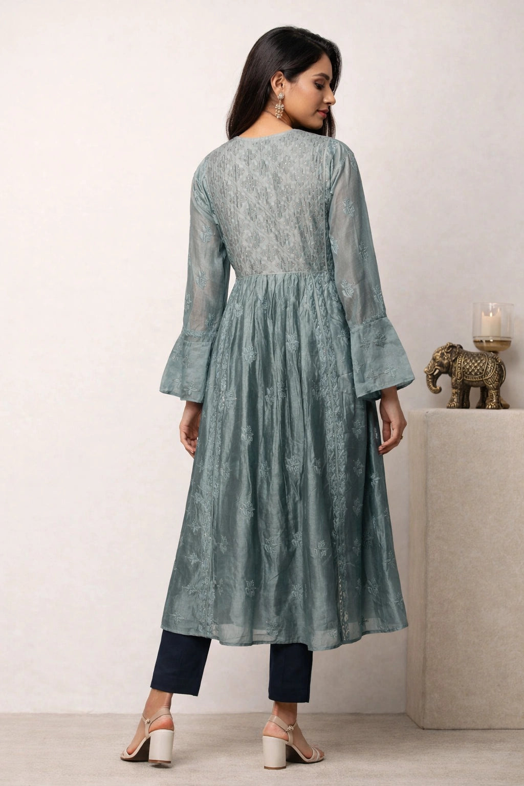 Woman wearing a light blue kurta with bell sleeves in a minimalistic setting.