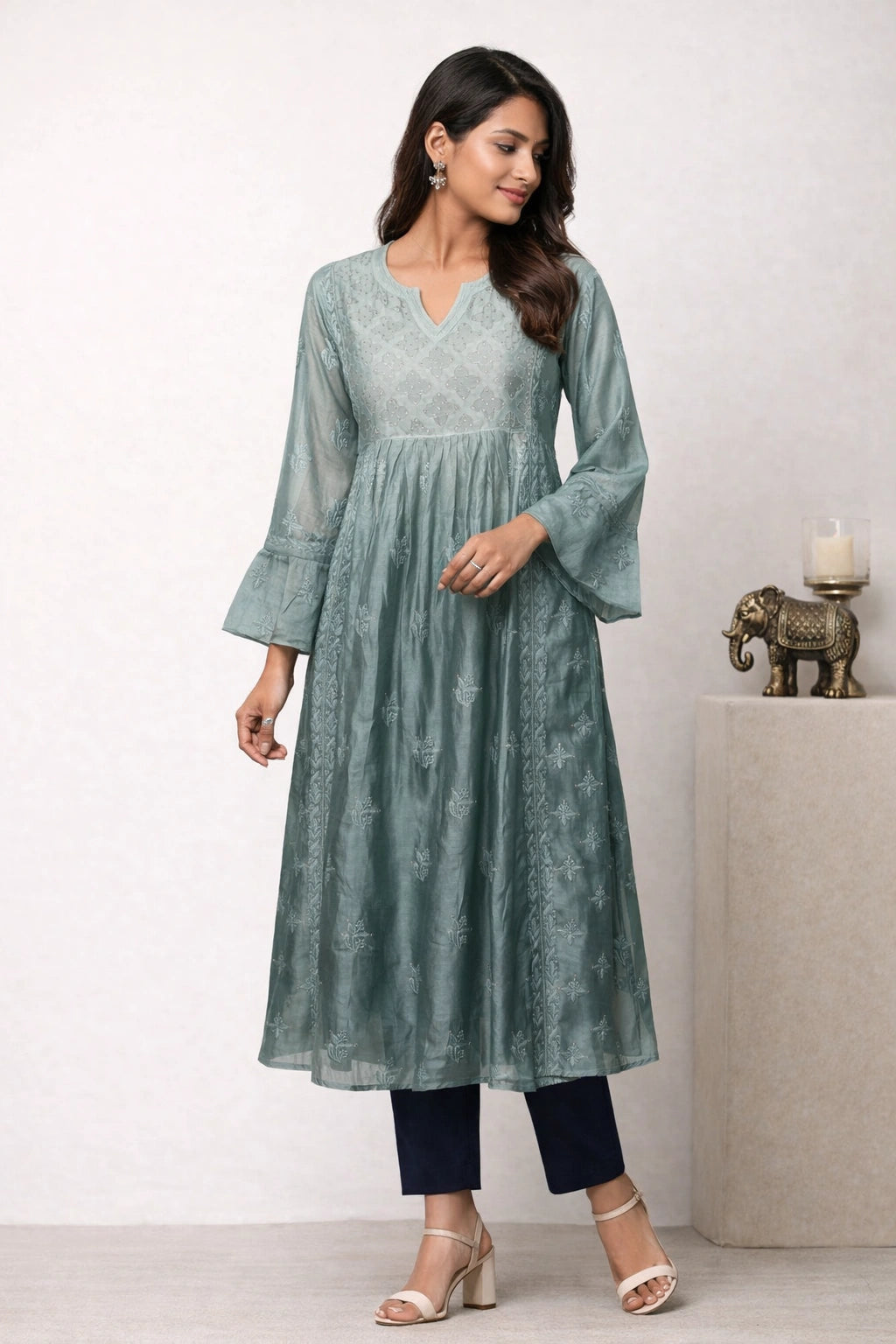 Woman wearing a green kurta with black pants against a white background