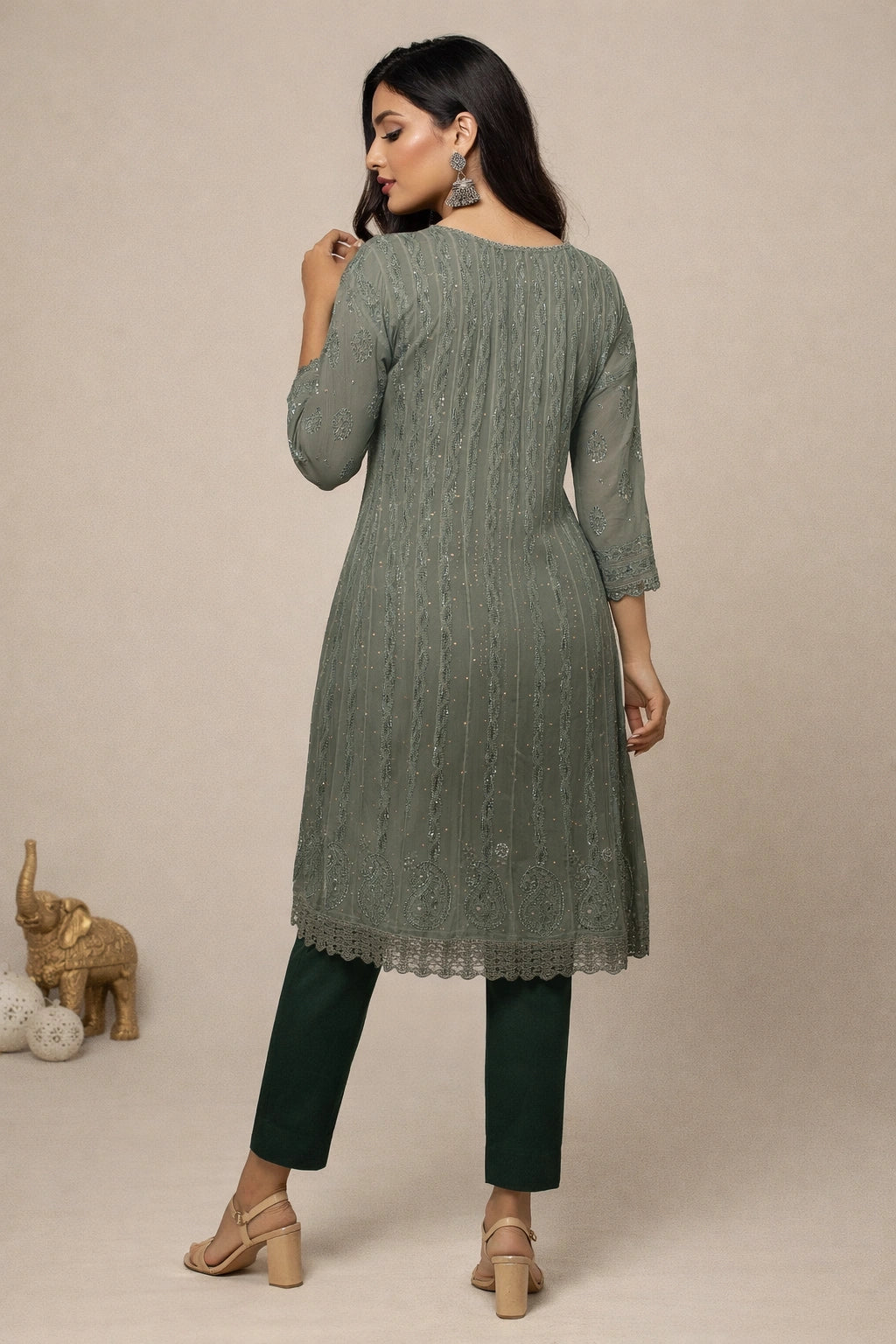 Woman wearing a green kurta with matching pants against a beige background