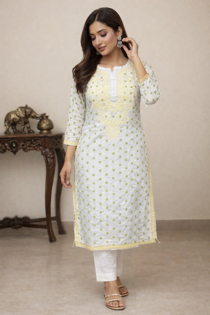 Woman wearing a chikan white and yellow traditional outfit with a beige background