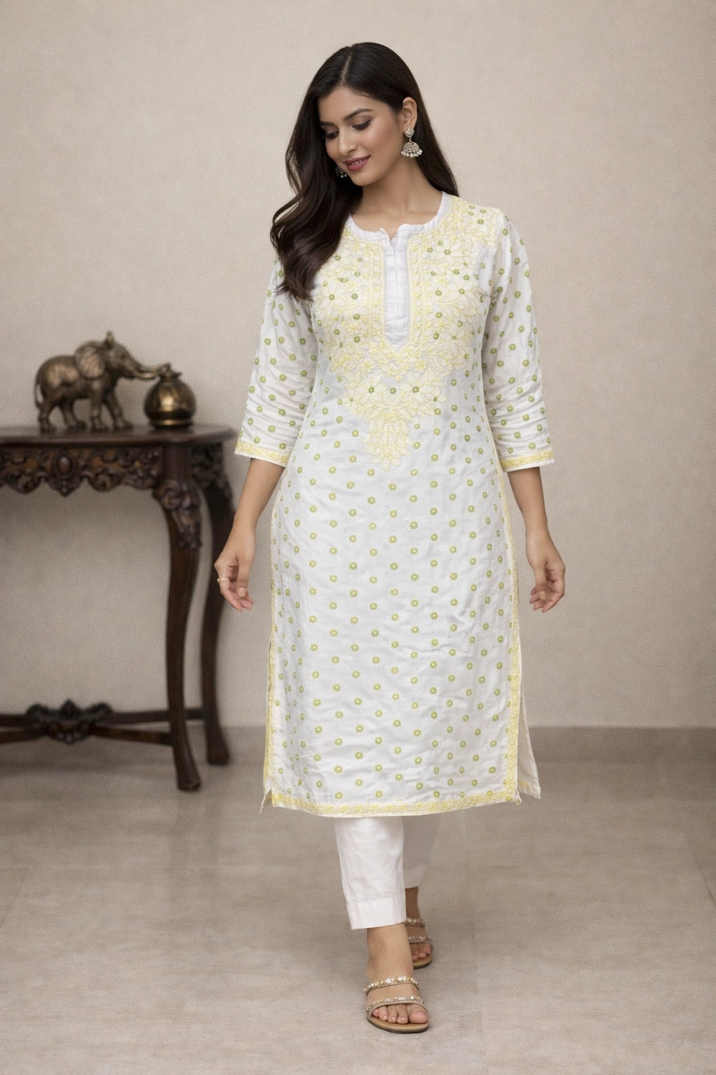 Woman wearing a lucknowi chikankari light-colored kurta with white pants in an indoor setting.