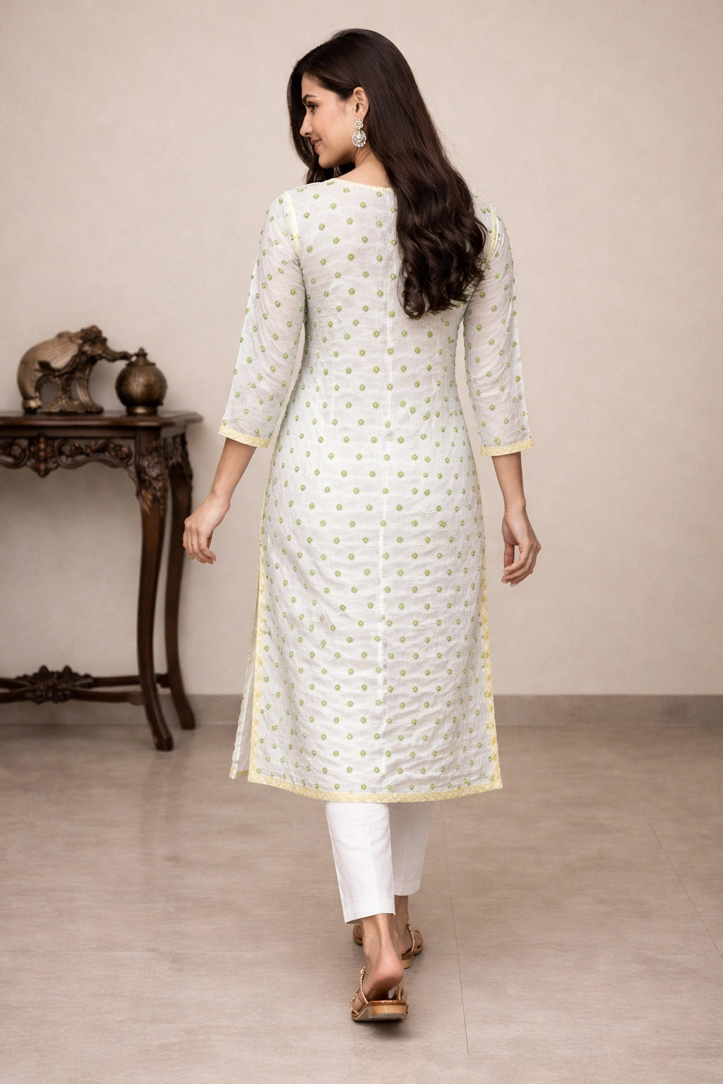 Woman wearing a embroidered white kurta with gold patterns in a minimalistic setting
