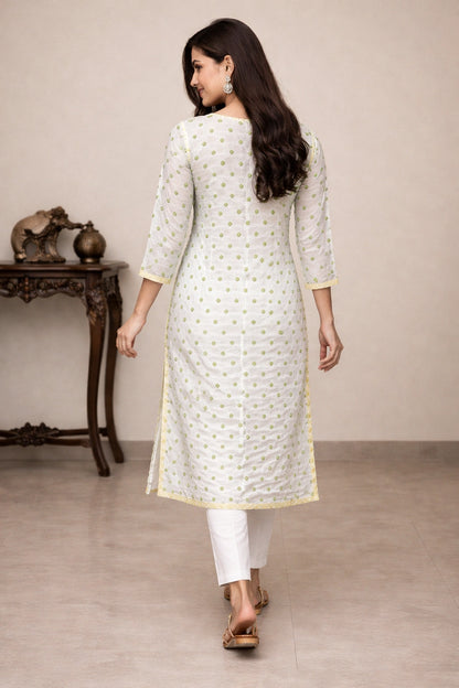 Woman wearing a embroidered white kurta with gold patterns in a minimalistic setting