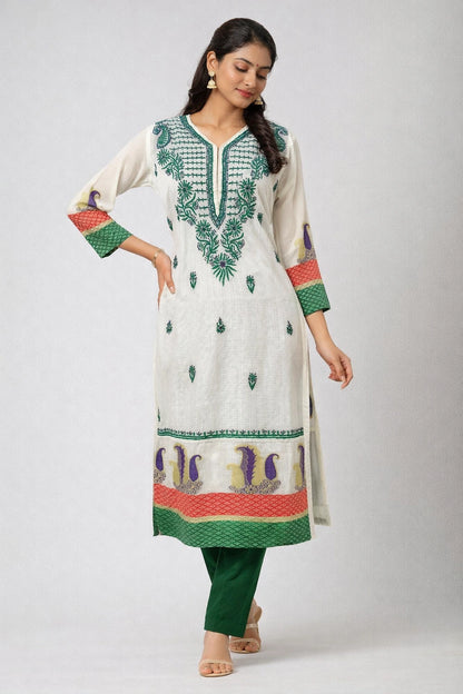 Woman wearing a white embroidered kurta with green and red details on a light gray background