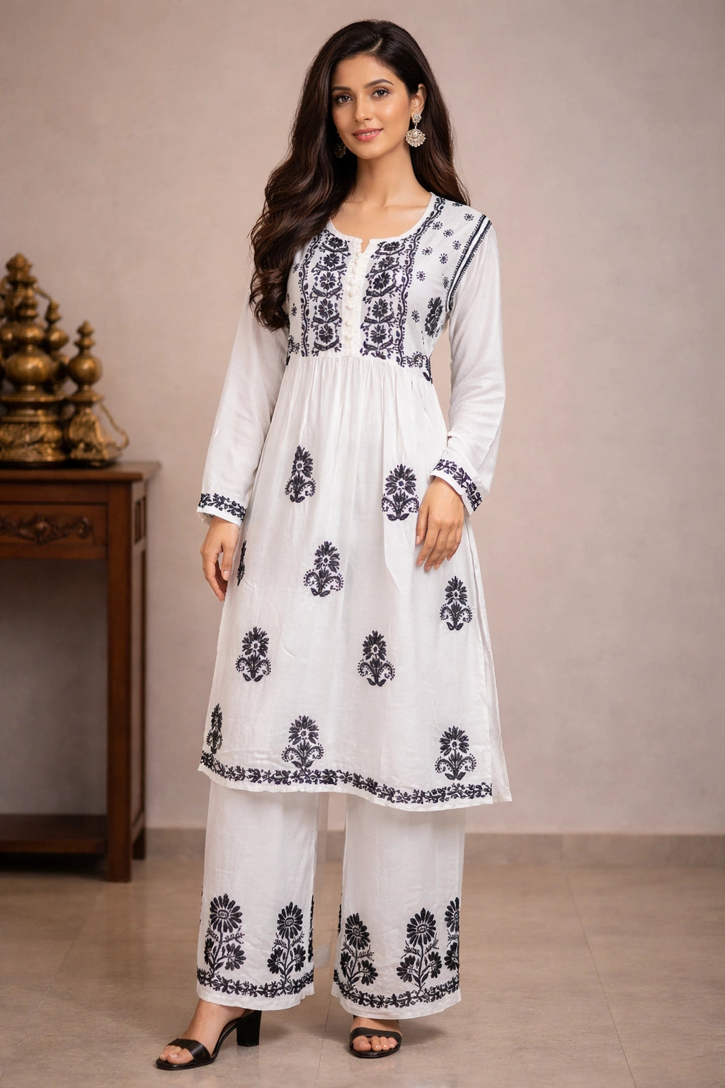 Woman wearing a white chikan outfit with black floral patterns in a neutral setting