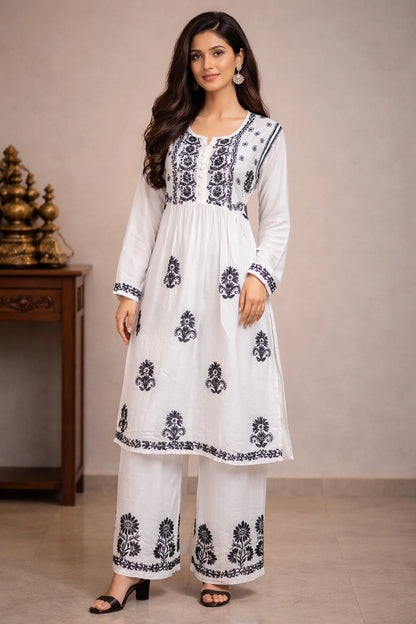 Woman wearing a white chikan outfit with black floral patterns in a neutral setting