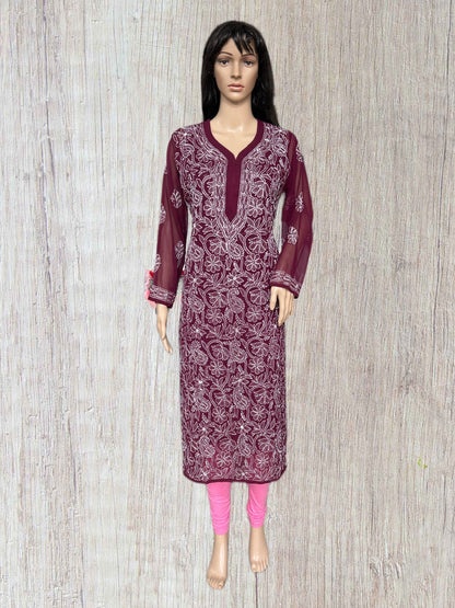 A mannequin wearing a long-sleeved maroon embroidered kurta with white floral patterns, paired with bright pink leggings, set against a light wood-textured background.