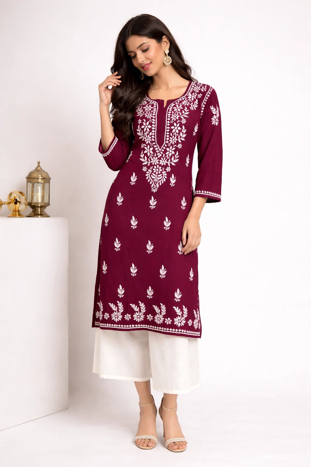 Woman wearing a maroon embroidered kurta with white pants on a white background
