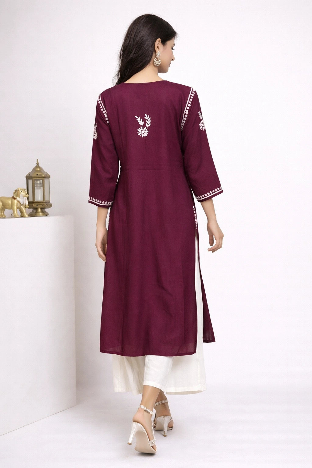 Woman wearing a maroon kurta with white embroidery on a white background