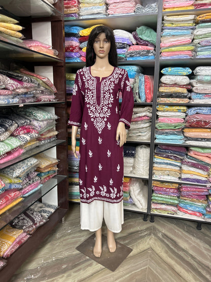 Mannequin wearing a maroon embroidered dress in a fabric store