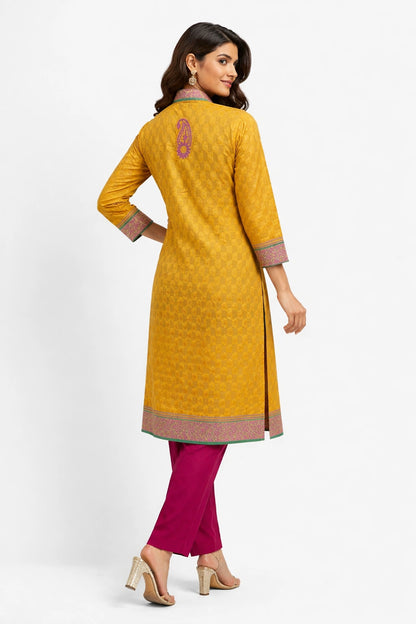 Lucknowi chikankari A woman modeling a mustard yellow kurta with a subtle geometric pattern, paired with magenta pants and beige heels, shown from a back-three-quarter view against a white studio background.