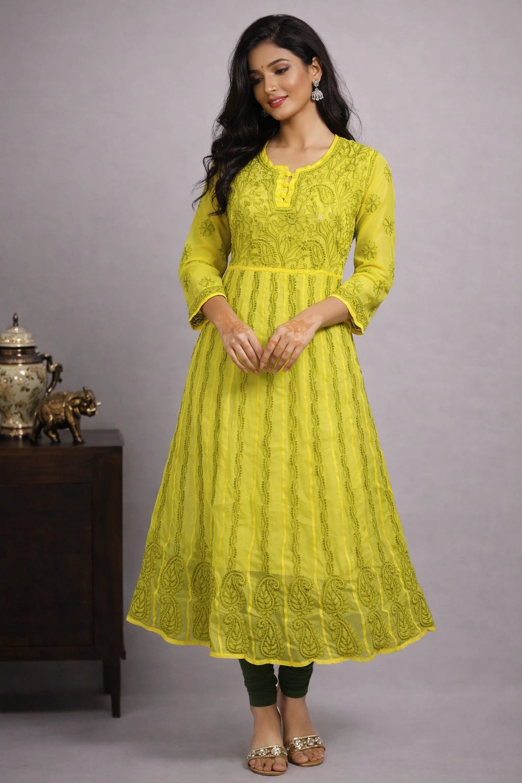 Woman wearing a yellow dress with intricate patterns against a gray background
