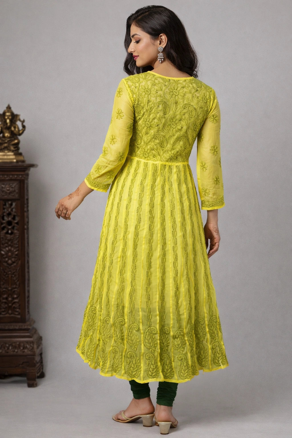 Woman wearing a bright yellow embroidered kurta against a gray background