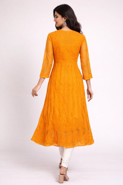 Woman wearing a bright orange lucknowi kurta with white pants on a white background