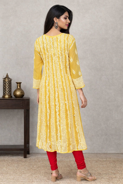 Woman wearing a yellow kurta with red pants against a gray background