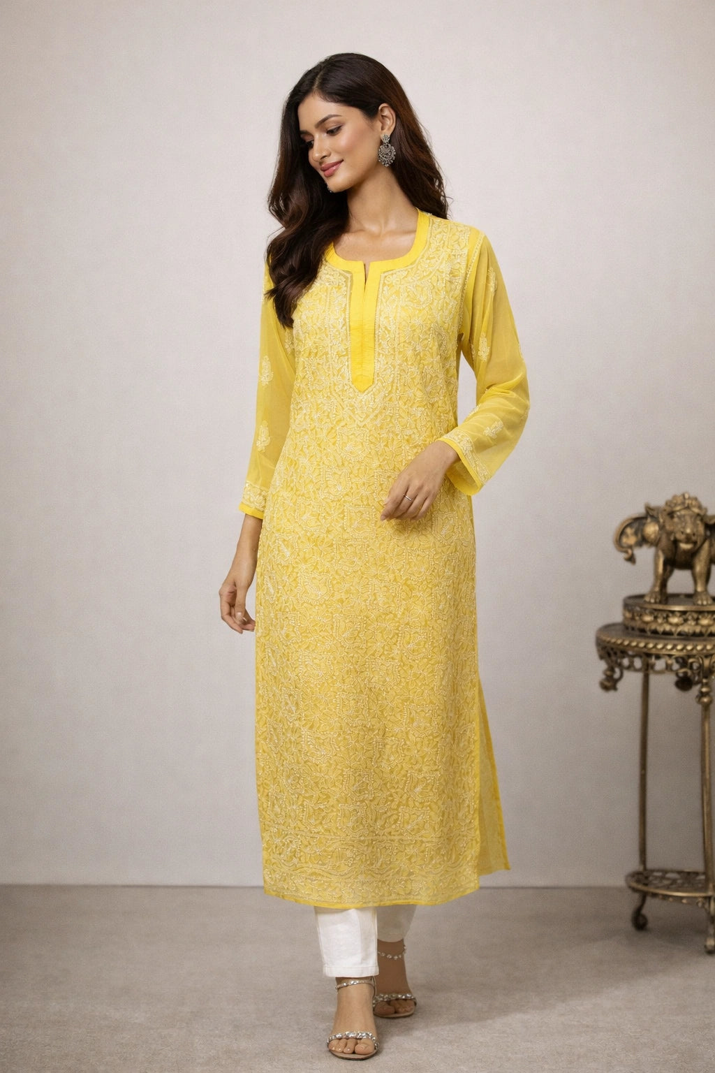 Woman wearing a yellow kurta with white pants against a plain background