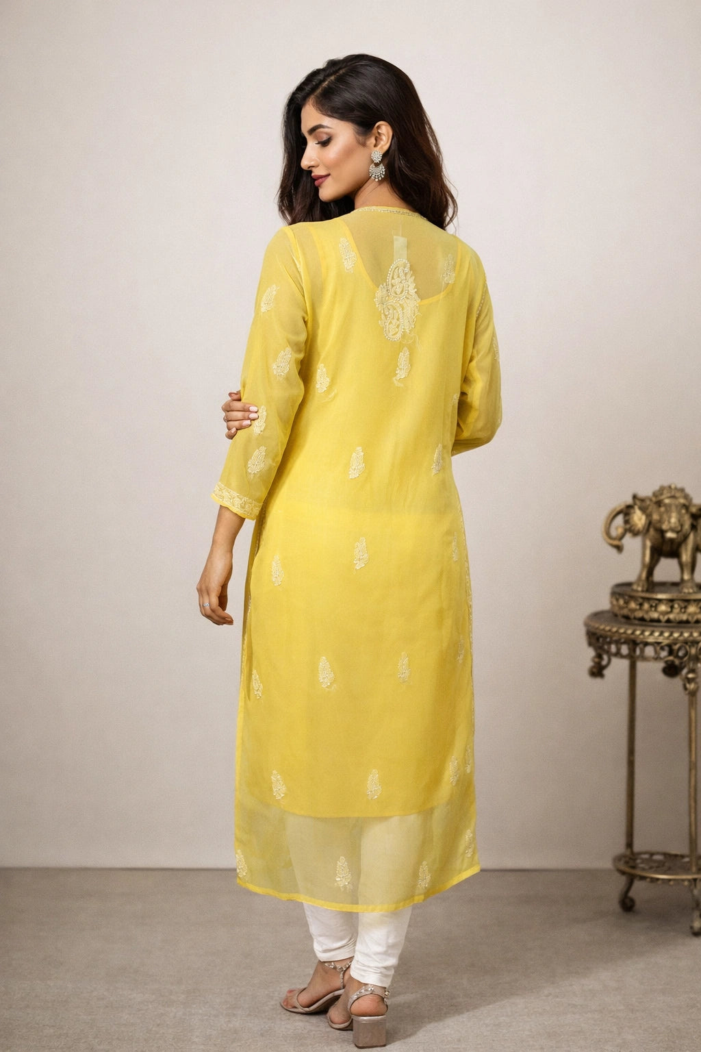 Woman wearing a yellow kurta with white patterns in a minimalistic setting.