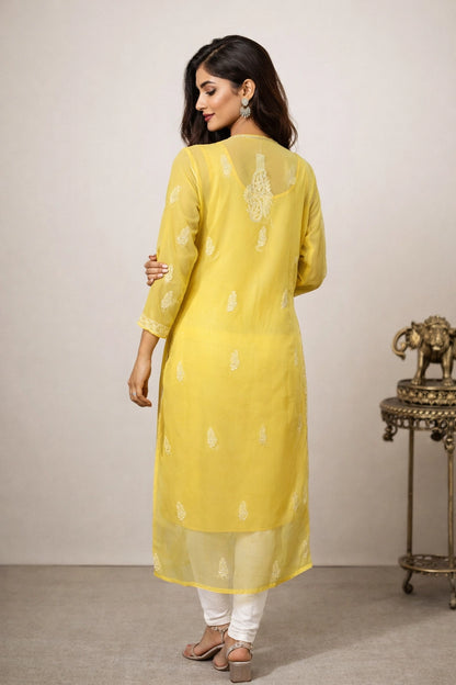 Woman wearing a yellow kurta with white patterns in a minimalistic setting.