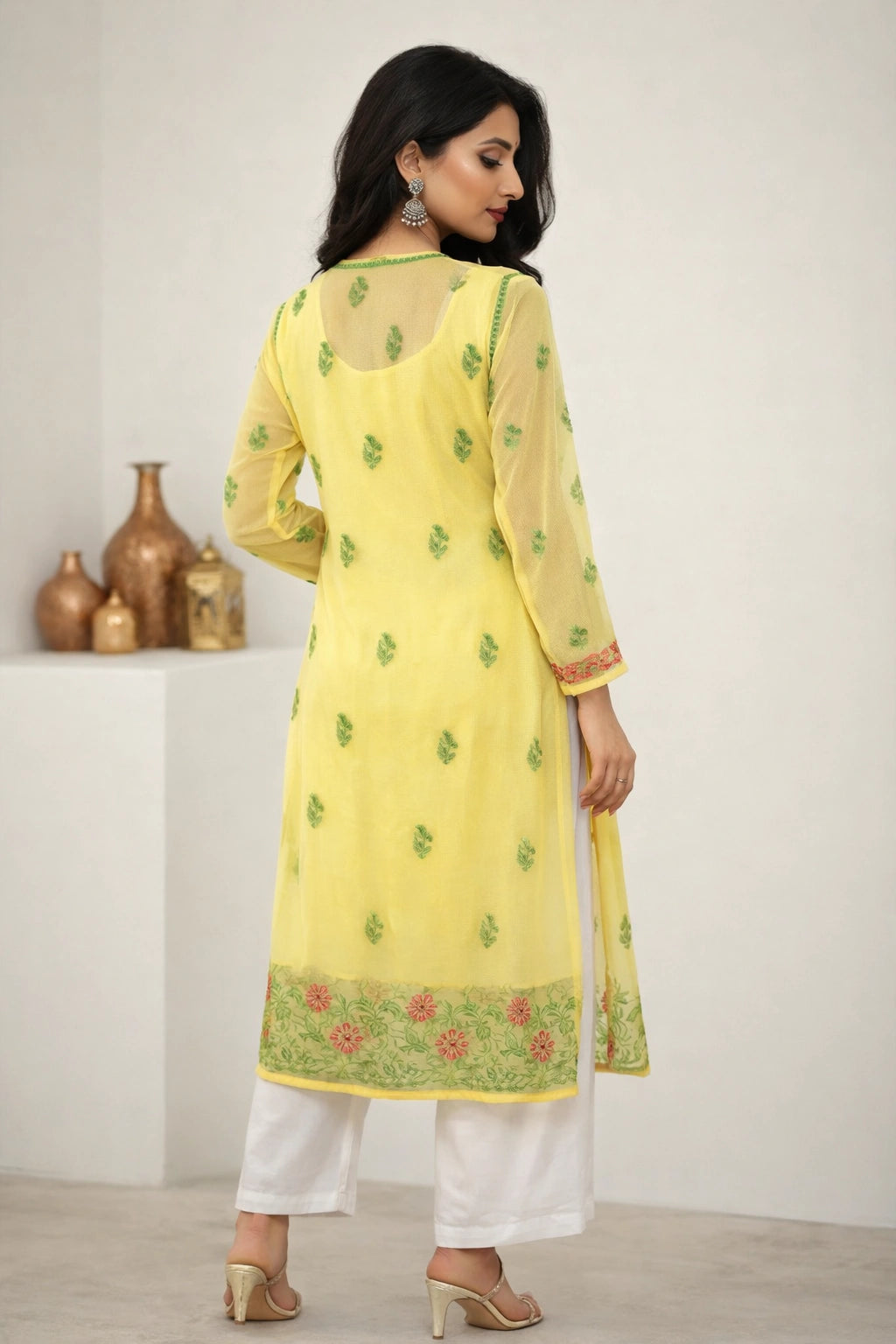 Woman wearing a chikankari yellow kurta with floral patterns in a minimalistic setting.