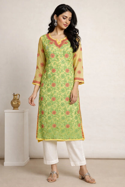 Woman wearing a lucknowi chikan green and yellow traditional outfit with white pants against a plain background