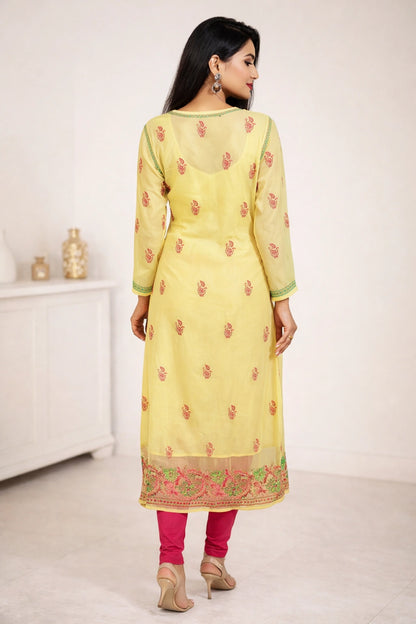Woman wearing a yellow embroidered kurta with pink pants in a minimalistic setting