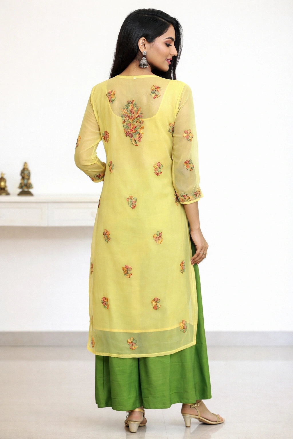 Woman wearing a yellow and green traditional outfit with floral embroidery on a white background