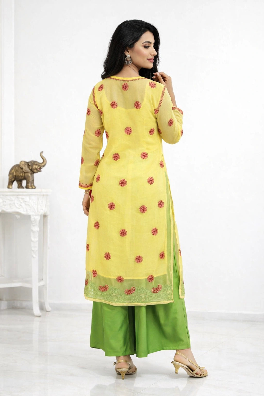 Woman wearing a yellow and green traditional outfit with red floral patterns on a white background