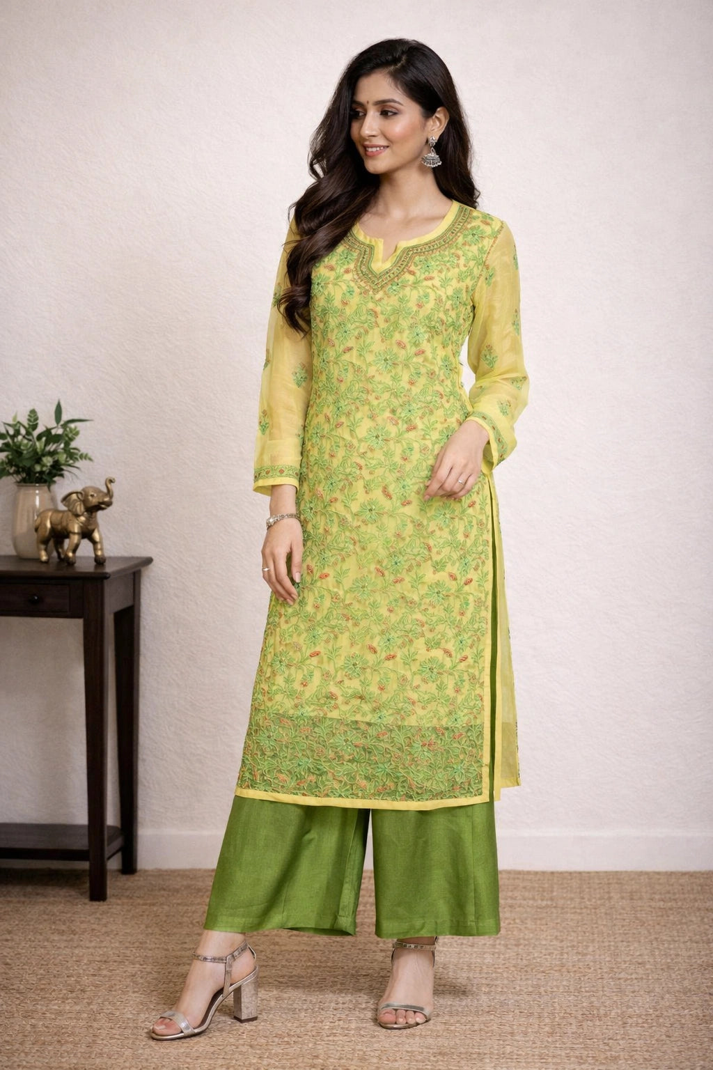 Woman wearing a green and yellow chikankari kurti with a plain background
