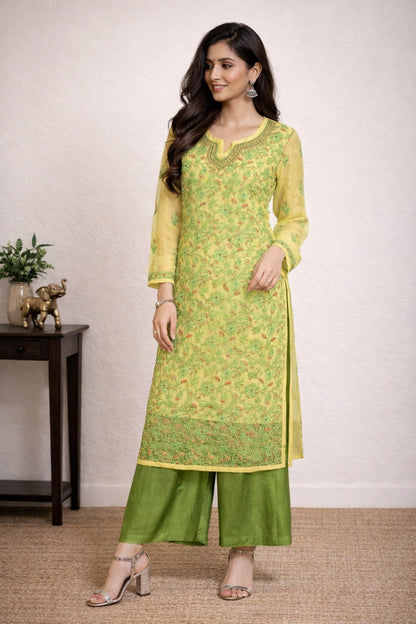 Woman wearing a green and yellow chikankari kurti with a plain background