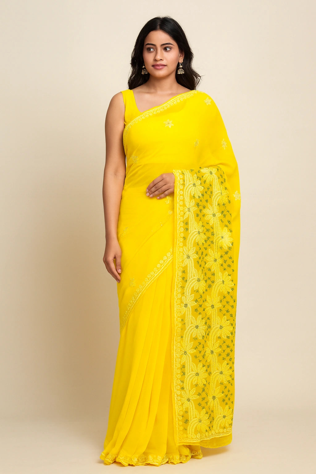 Woman wearing a lucknowi chikankari yellow saree with a floral border on a beige background
