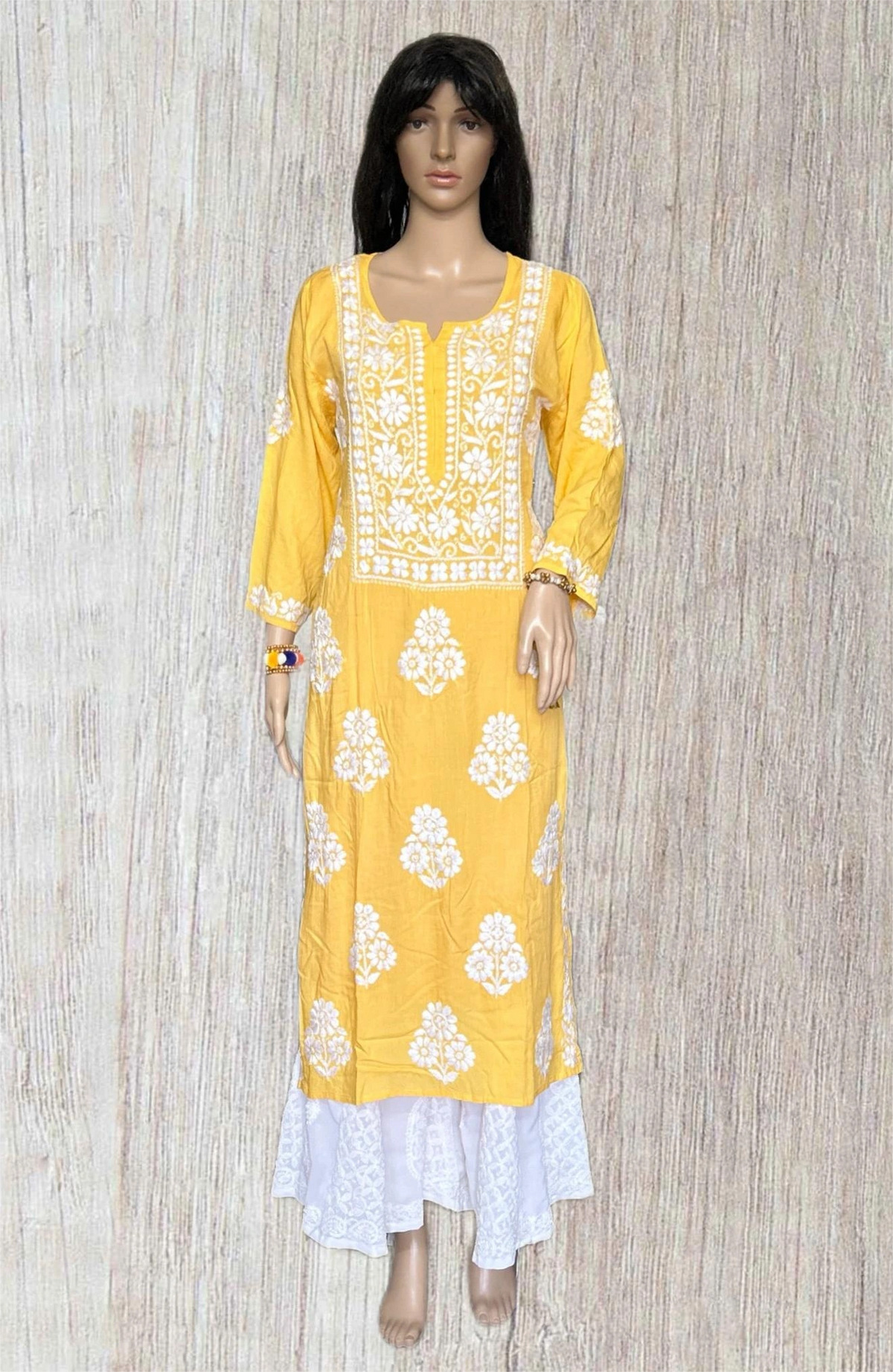 A woman modeling a light yellow kurta  wooden gray background.