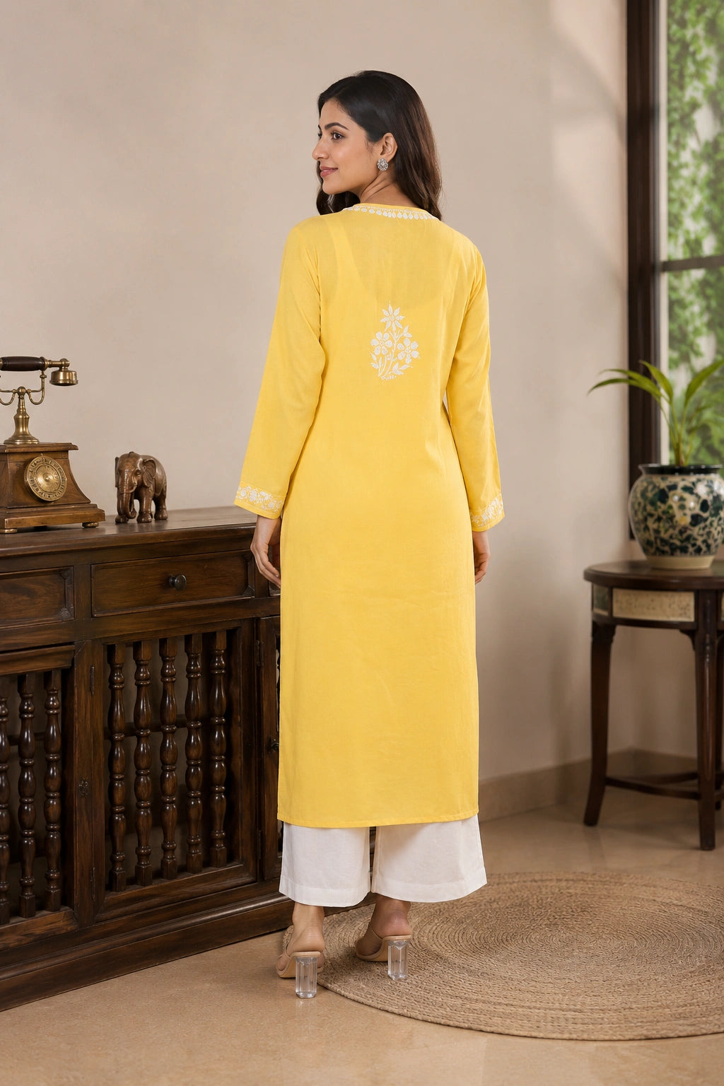 Woman wearing a yellow kurta with white pants in an indoor setting.