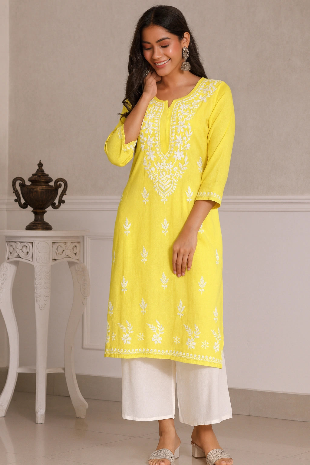 Woman wearing a yellow embroidered kurta with white pants in an indoor setting.