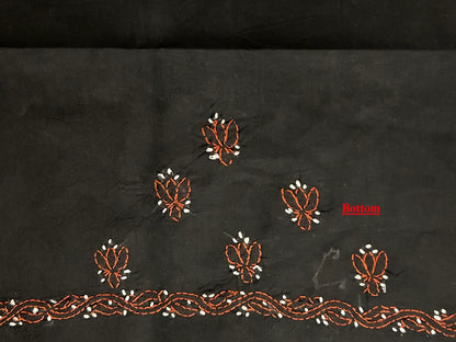 Black fabric with intricate brown and white embroidery on a dark background