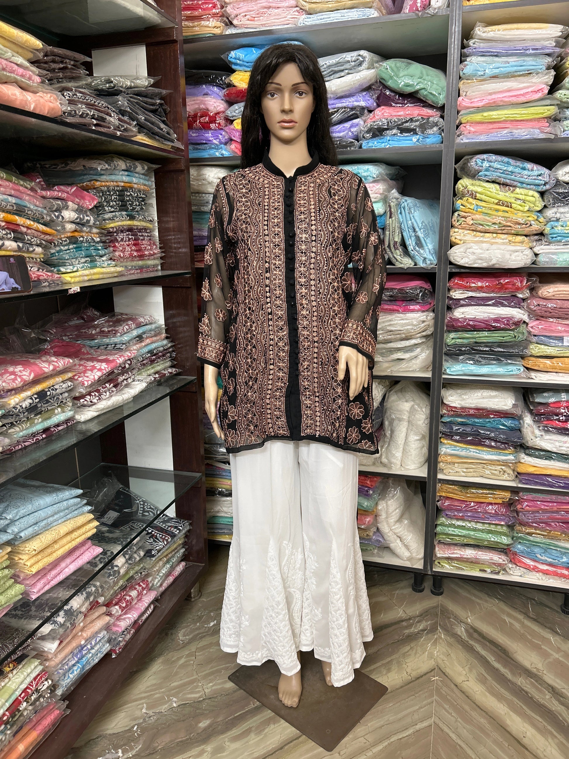 lucknowi chikankari Mannequin wearing a patterned top and white pants in a fabric store.