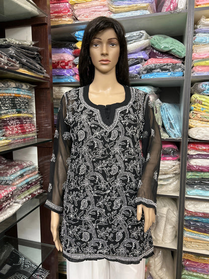 Mannequin wearing a black and white embroidered top in a fabric store.