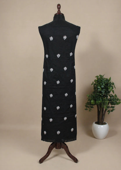 Black dress with white floral patterns on a mannequin against a beige background