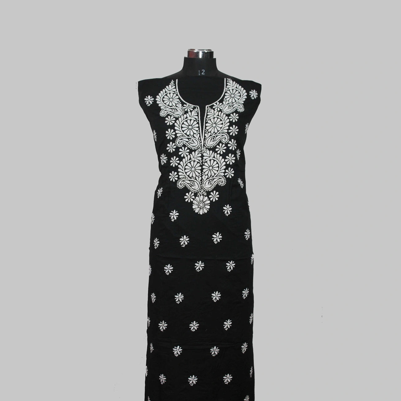 Black dress with white floral embroidery on a mannequin against a gray background