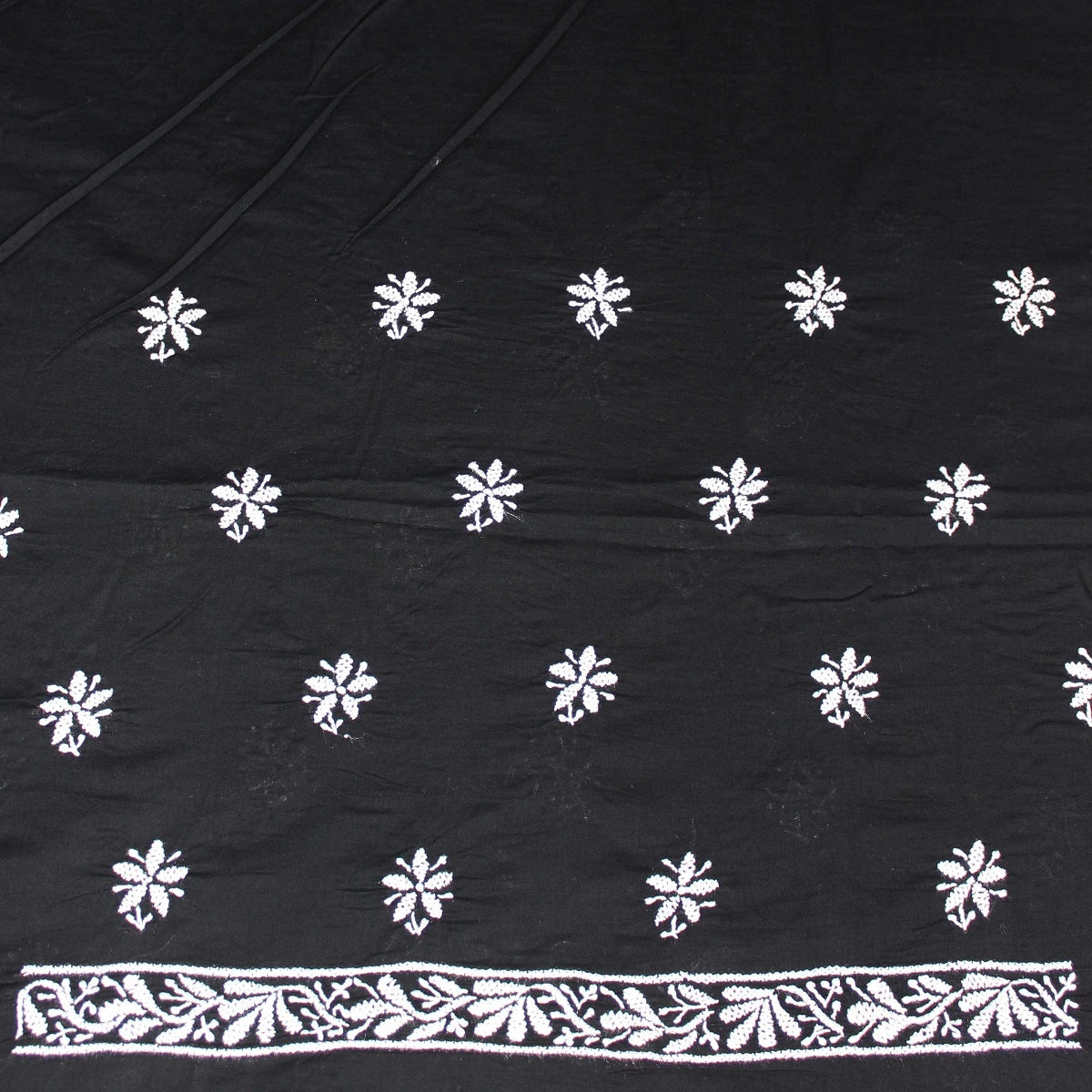 Black fabric with white floral patterns and a decorative border.