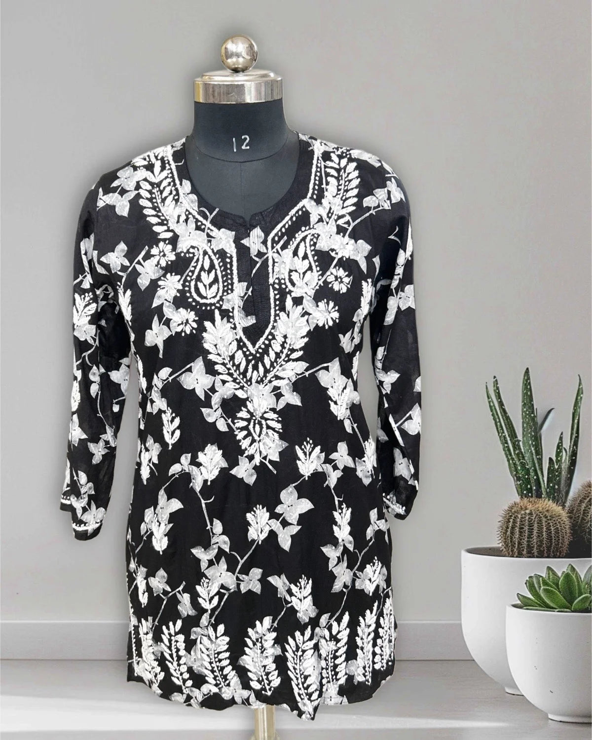 lucknowi chikankari Black dress with white floral pattern on a mannequin against a gray background