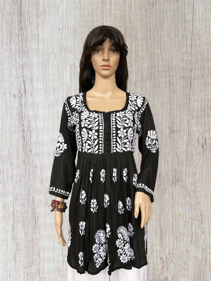 lucknowi chikankari Black dress with white floral patterns on a mannequin against a wooden background
